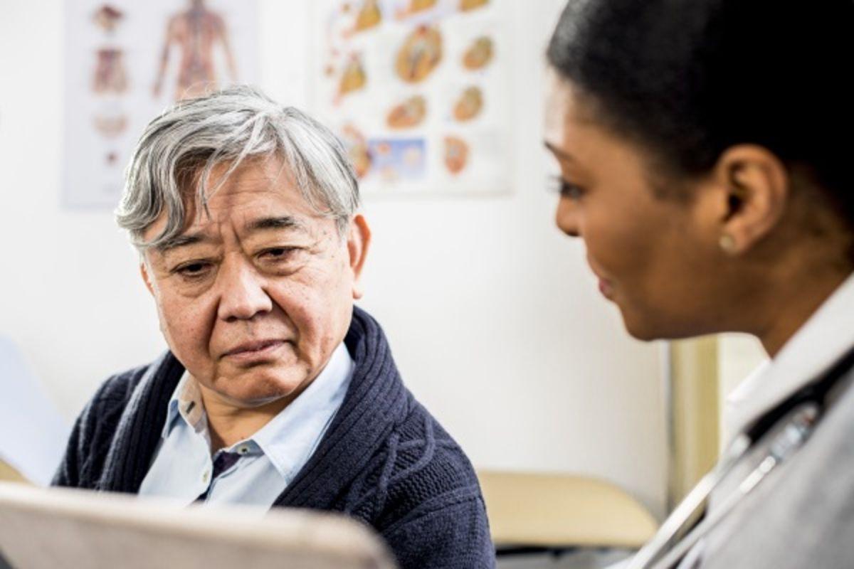 Female HCP and male patient review information on a digital tablet.